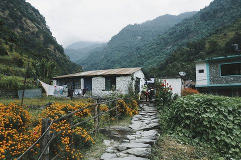 Stone‑walled Himalayan tea house with outdoor tables and tent against misty mountain slopes