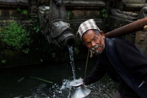 an-ond-man-collecting-water-from-a-traditional-tap-in-nepal