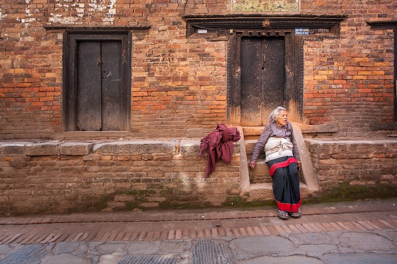 an-old-women-taking-rest-in-street-of-bhaktapur