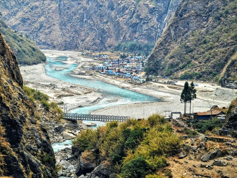 Bright yellow and blue tea house buildings along a green river valley framed by steep cliffs