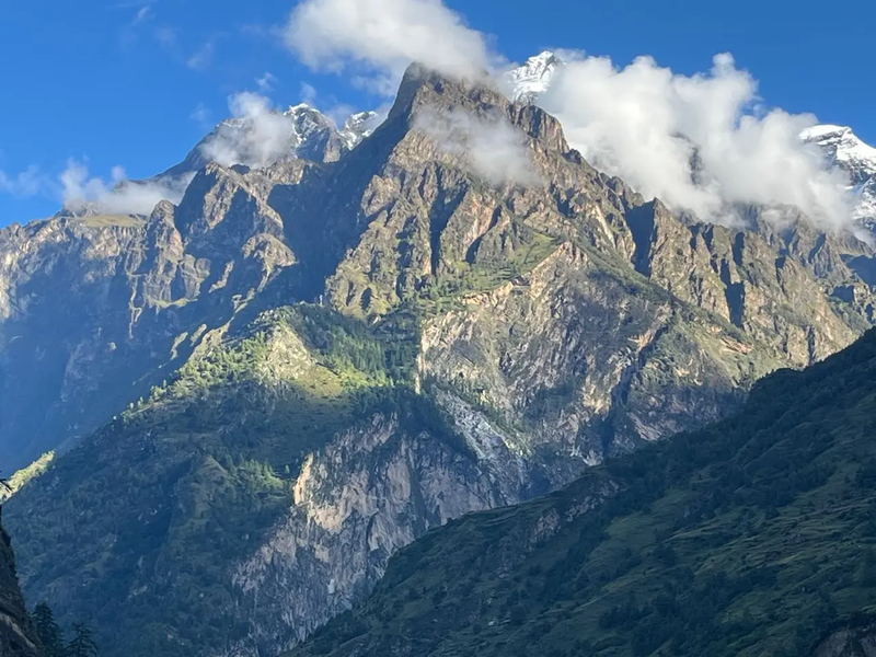 Mount Manaslu covered with drifting clouds under a bright sunny sky, showcasing the majestic Himalayan peak in Nepal.