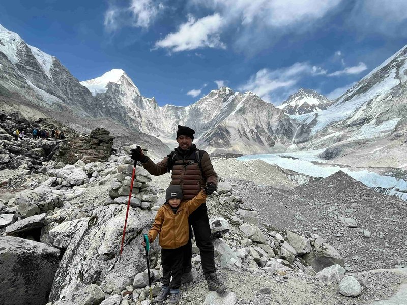 Father and child celebrating trekking success at Pikey Peak with snowy Himalayan peaks and glacier backdrop in Nepal