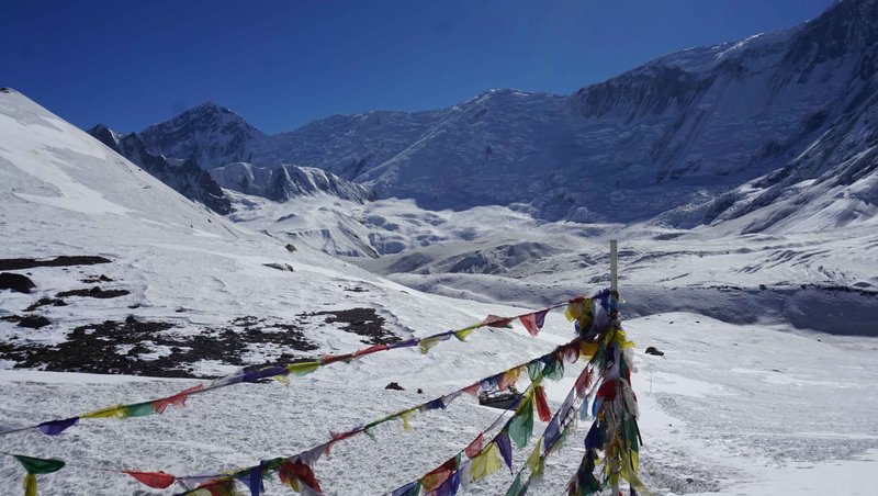 Colorful Tibetan prayer flags fluttering against backdrop of Annapurna mountains during Nepal trek