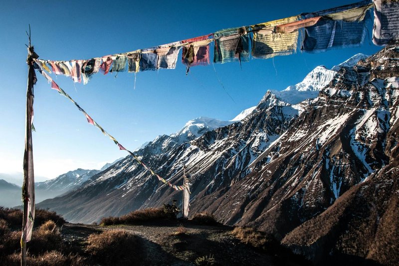 prayer flags fluttering and snow‑capped peaks beyond