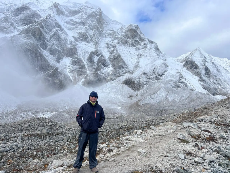 A lone trekker standing in front of Mount Manaslu, admiring the snow-covered peak under a clear blue sky in the Himalayas of Nepal.